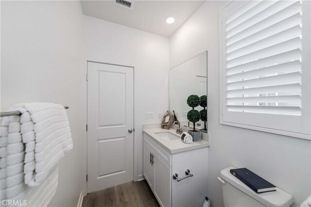 bathroom with hardwood / wood-style floors, toilet, and vanity