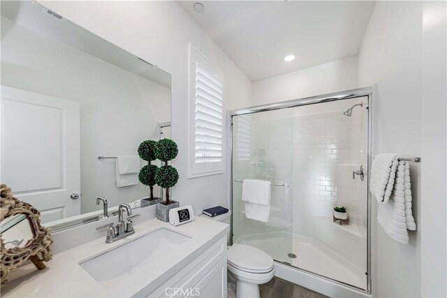 bathroom featuring vanity, toilet, hardwood / wood-style flooring, and a shower with door