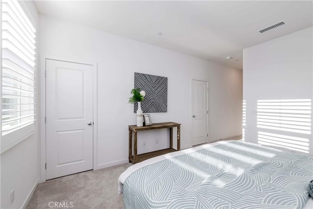 bedroom with baseboards, visible vents, and light colored carpet