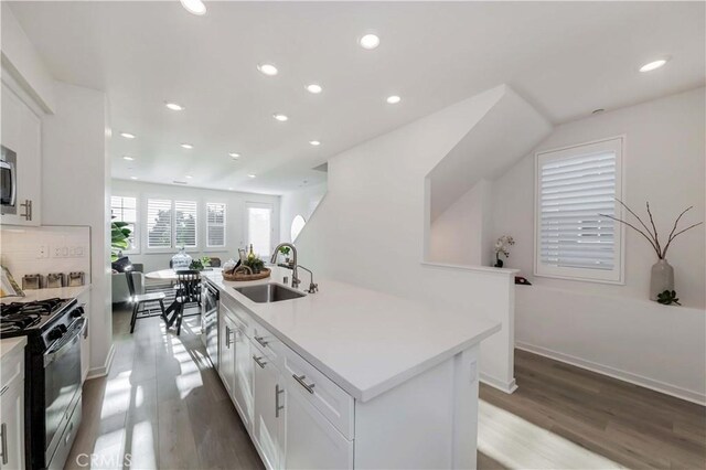 kitchen with light hardwood / wood-style floors, an island with sink, stainless steel appliances, white cabinets, and sink