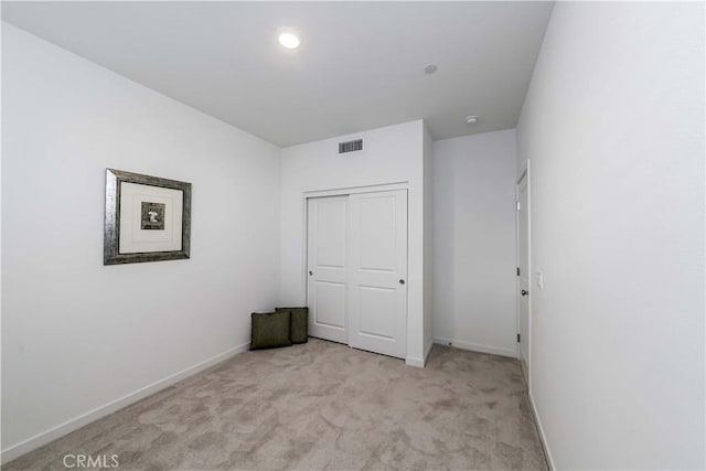 unfurnished bedroom featuring light colored carpet and a closet