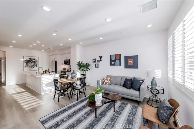 living room with a healthy amount of sunlight, light wood finished floors, visible vents, and recessed lighting