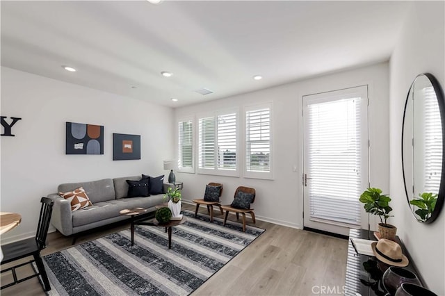 living room with light wood-type flooring, visible vents, baseboards, and recessed lighting