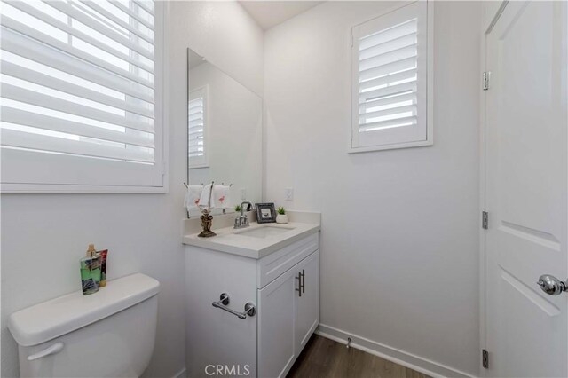 bathroom featuring toilet, a healthy amount of sunlight, wood-type flooring, and vanity