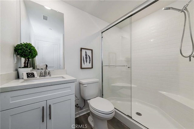 bathroom with a stall shower, visible vents, toilet, wood finished floors, and vanity