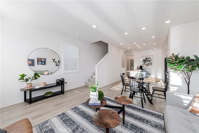 living room with baseboards, light wood finished floors, stairway, and recessed lighting