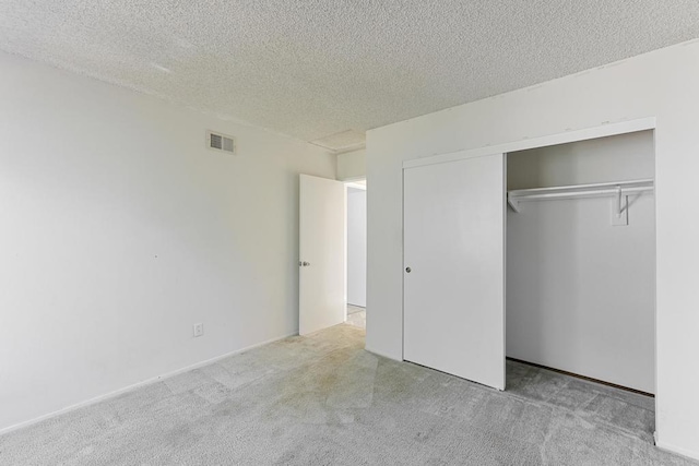 unfurnished bedroom with light carpet, a textured ceiling, and a closet