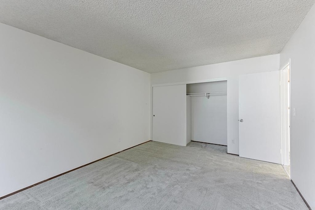 unfurnished bedroom featuring a textured ceiling, light colored carpet, and a closet