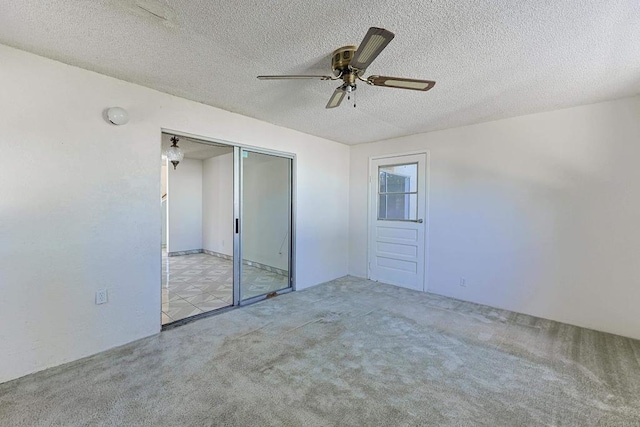 unfurnished bedroom featuring light carpet, a textured ceiling, a closet, and ceiling fan