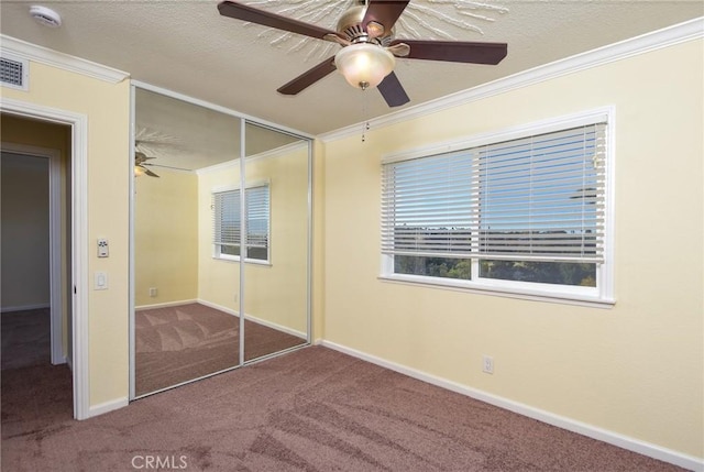 unfurnished bedroom with ceiling fan, a closet, carpet, and crown molding