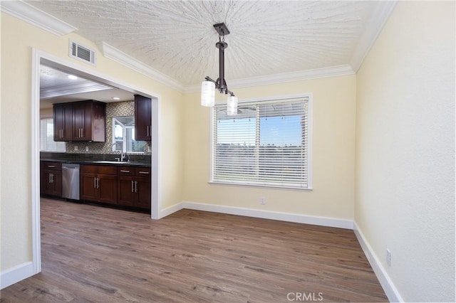 kitchen featuring dishwasher, dark wood-type flooring, hanging light fixtures, backsplash, and crown molding