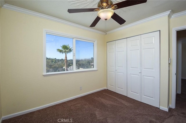 unfurnished bedroom featuring ceiling fan, dark carpet, and crown molding