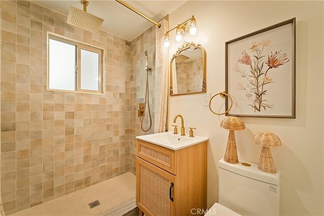 bathroom with vanity, toilet, and a tile shower