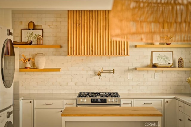 kitchen with wooden counters, range, stacked washer / drying machine, and backsplash