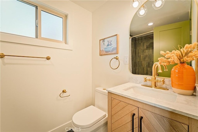 bathroom featuring vanity, toilet, and a tile shower