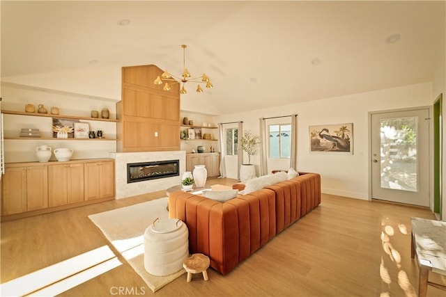 living room with vaulted ceiling, an inviting chandelier, and light hardwood / wood-style flooring