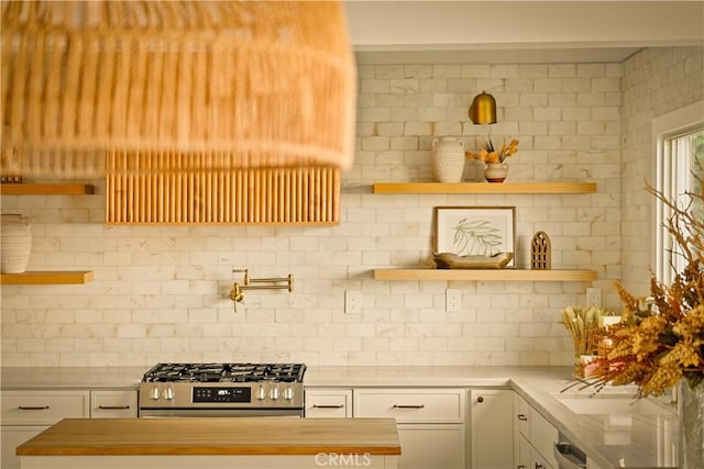 kitchen with white cabinetry, butcher block countertops, decorative backsplash, and stove