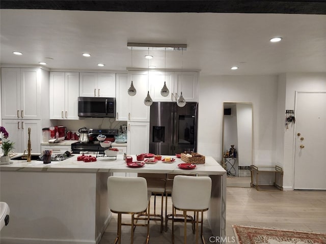 kitchen featuring white cabinetry, appliances with stainless steel finishes, light wood-type flooring, a breakfast bar, and sink