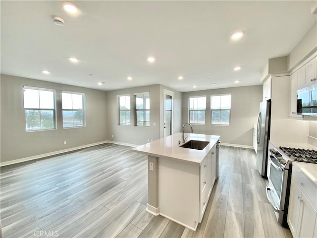 kitchen featuring white cabinetry, sink, a healthy amount of sunlight, an island with sink, and appliances with stainless steel finishes