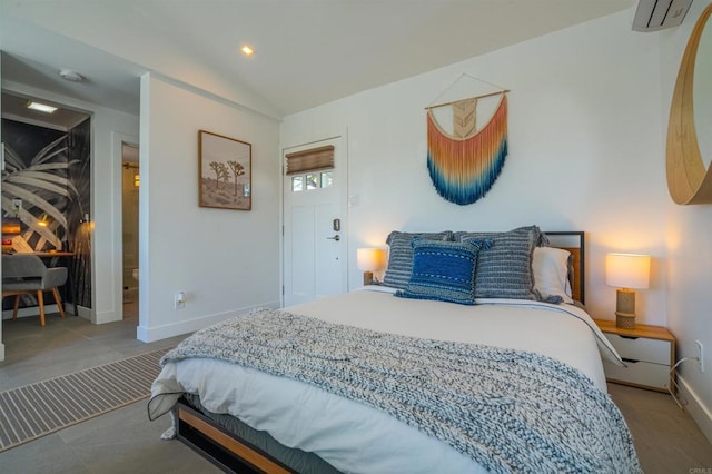 bedroom featuring an AC wall unit, ensuite bathroom, light tile patterned floors, and lofted ceiling