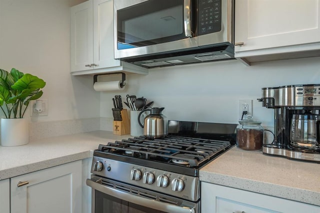 kitchen with white cabinets, light stone countertops, and appliances with stainless steel finishes