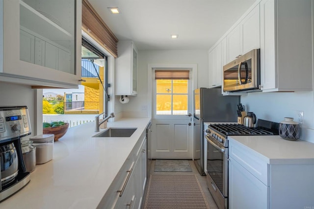 kitchen with a healthy amount of sunlight, sink, white cabinets, and stainless steel appliances