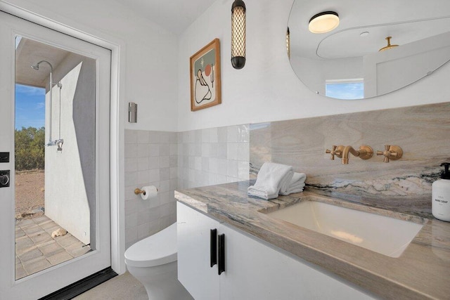 bathroom featuring vanity, a healthy amount of sunlight, toilet, and tile walls