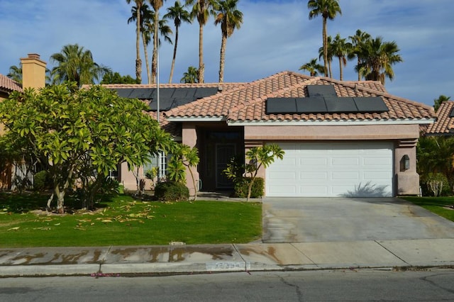 view of front of home featuring a garage, a front yard, and solar panels