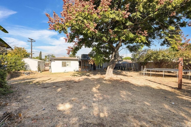 view of yard with a trampoline and a storage unit