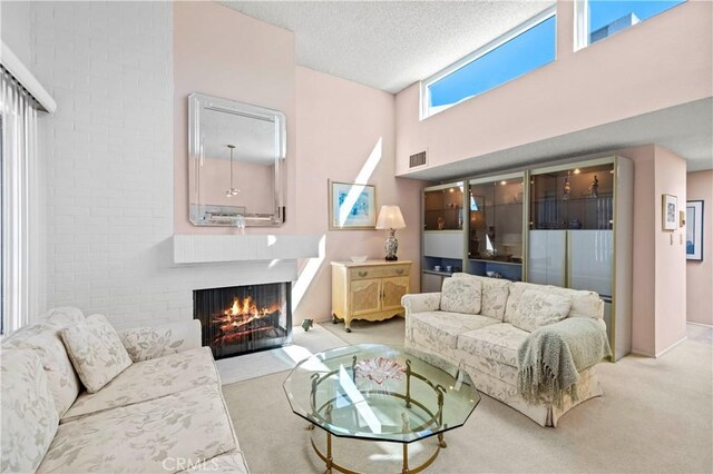 carpeted living room featuring a brick fireplace, a textured ceiling, and a high ceiling