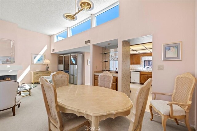 dining space featuring light colored carpet, a textured ceiling, and a high ceiling