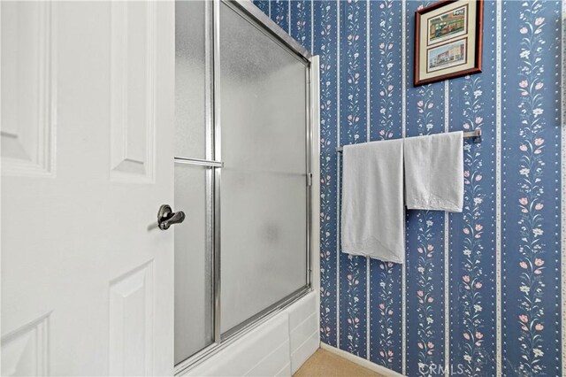 bathroom featuring combined bath / shower with glass door