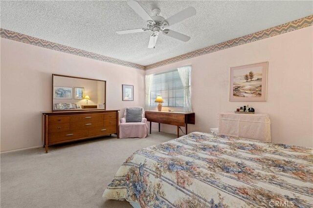 carpeted bedroom with ceiling fan and a textured ceiling