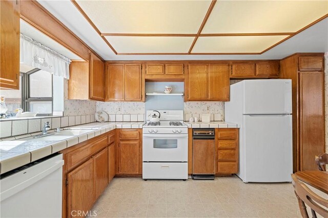 kitchen with tasteful backsplash, sink, tile counters, and white appliances