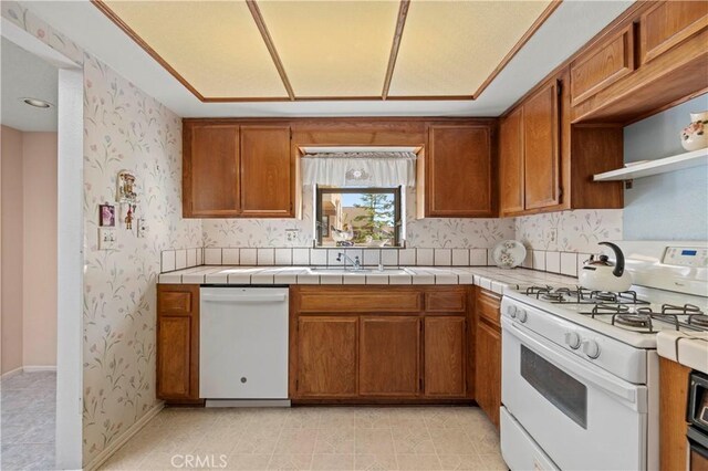 kitchen featuring white appliances, tile counters, and sink