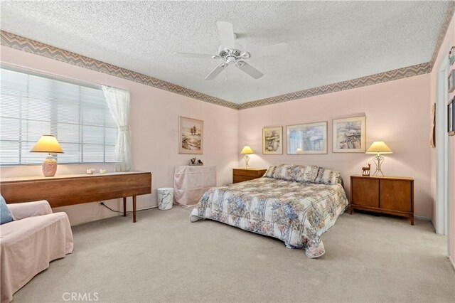 bedroom featuring ceiling fan, carpet floors, and a textured ceiling