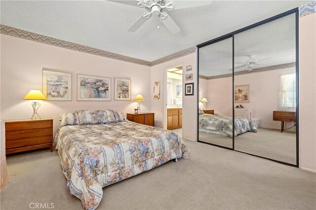 carpeted bedroom with ceiling fan, ensuite bathroom, a textured ceiling, and a closet