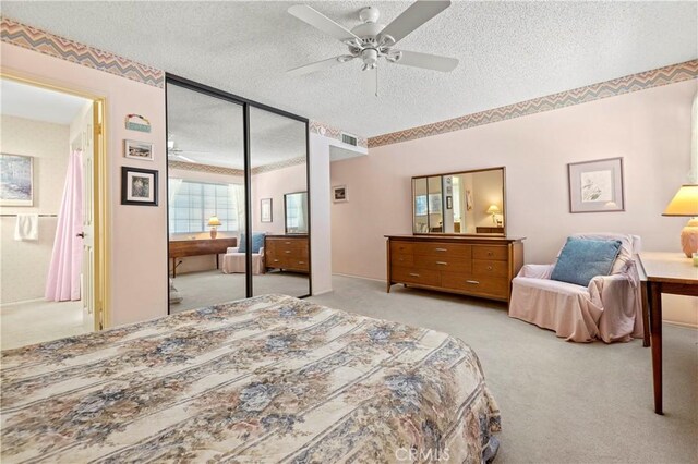 carpeted bedroom with ceiling fan, a closet, and a textured ceiling