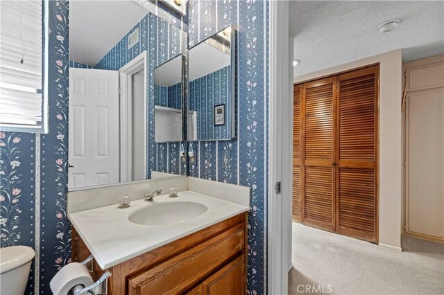 bathroom with vanity, toilet, and a textured ceiling