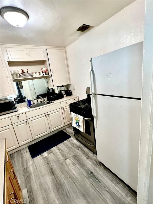 kitchen with white cabinetry, sink, light hardwood / wood-style flooring, white refrigerator, and range