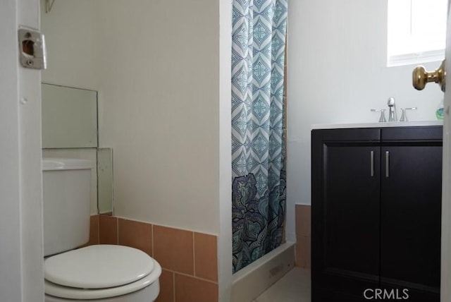 bathroom with vanity, toilet, walk in shower, and tile walls