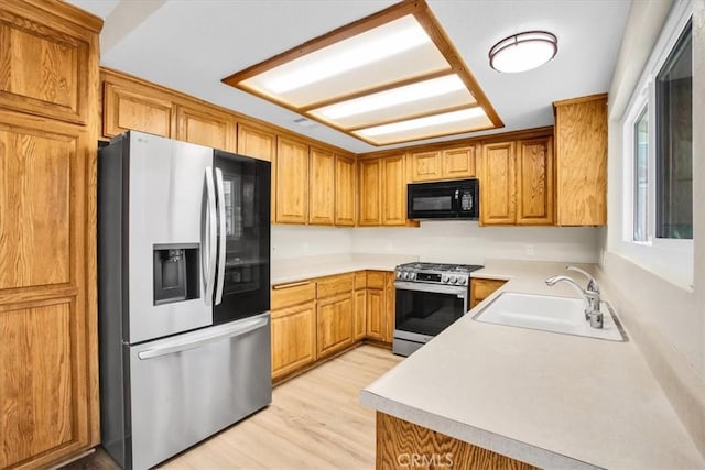 kitchen with sink, stainless steel appliances, and light hardwood / wood-style floors