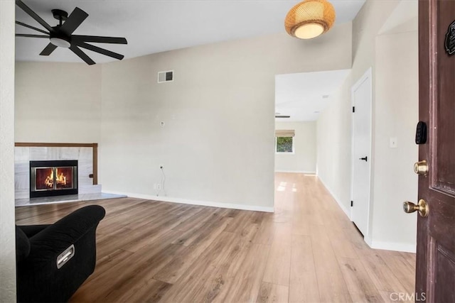 living room featuring a fireplace, light hardwood / wood-style floors, and ceiling fan