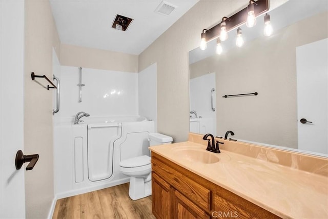 bathroom featuring a tub, hardwood / wood-style floors, vanity, and toilet