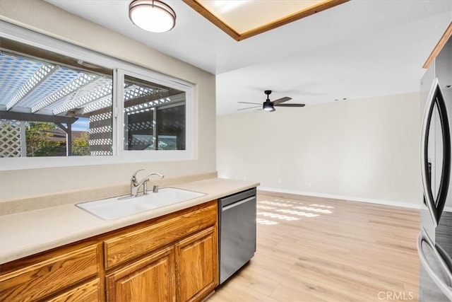 kitchen with appliances with stainless steel finishes, light hardwood / wood-style flooring, ceiling fan, and sink