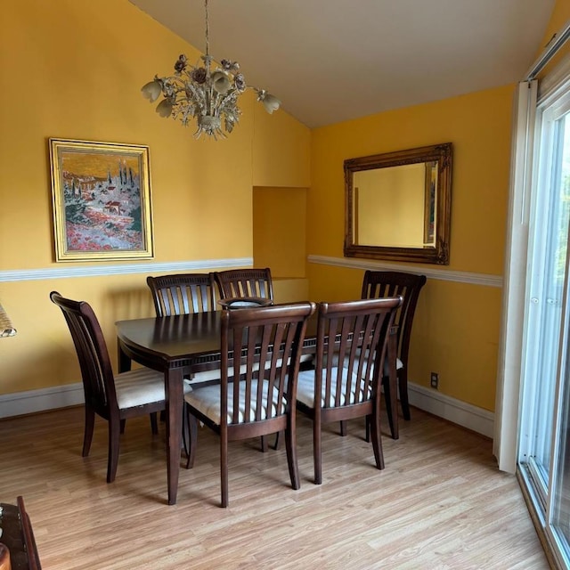 dining space featuring lofted ceiling, a notable chandelier, and light hardwood / wood-style flooring