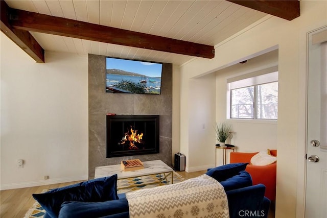 living room with a fireplace, light wood-type flooring, and beamed ceiling