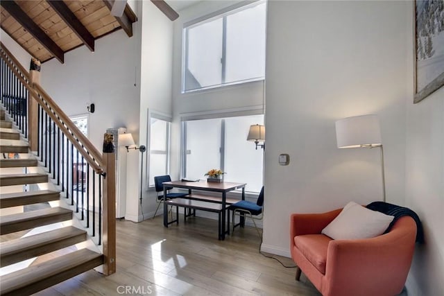 stairway featuring wooden ceiling, hardwood / wood-style floors, high vaulted ceiling, and a healthy amount of sunlight