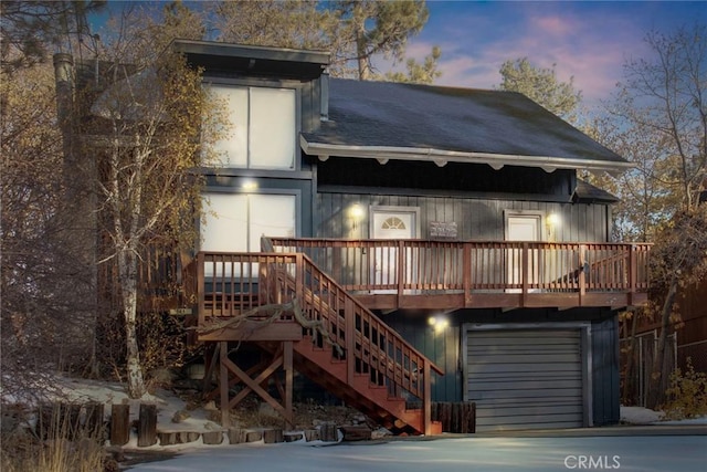 back house at dusk featuring a garage and a deck