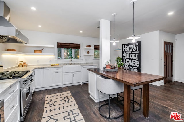 kitchen with decorative light fixtures, sink, white cabinets, wall chimney range hood, and high end stove